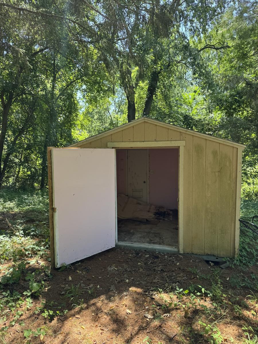 Shed before tear-down, yellow siding with door open