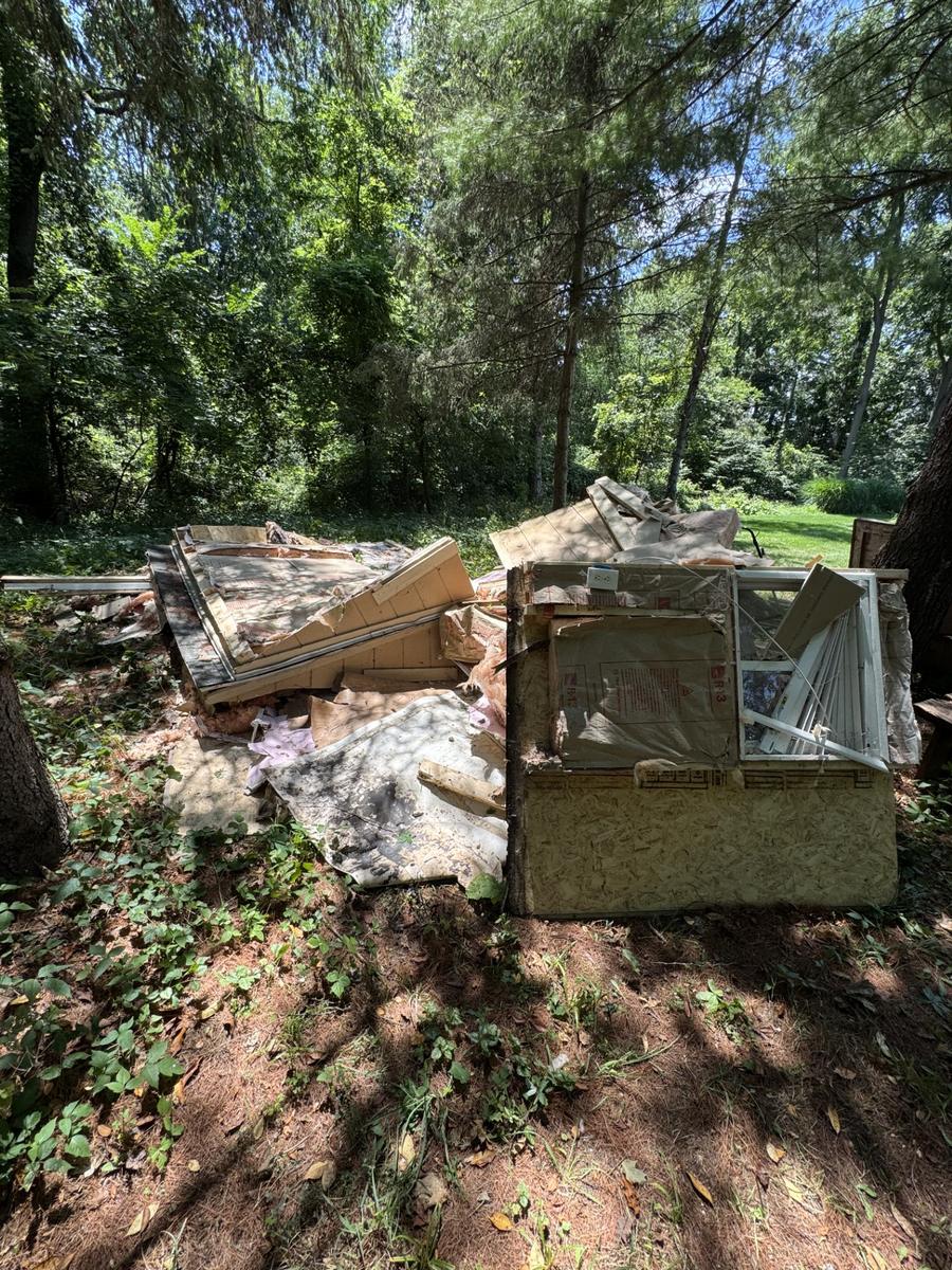 Shed during tear-down, walls and roof broken down into a debris pile