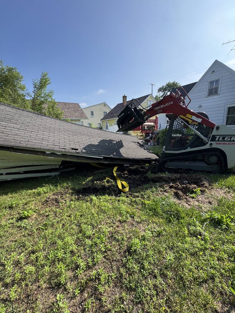 AJ's Demo Solutions track loader pulling down a garage roof